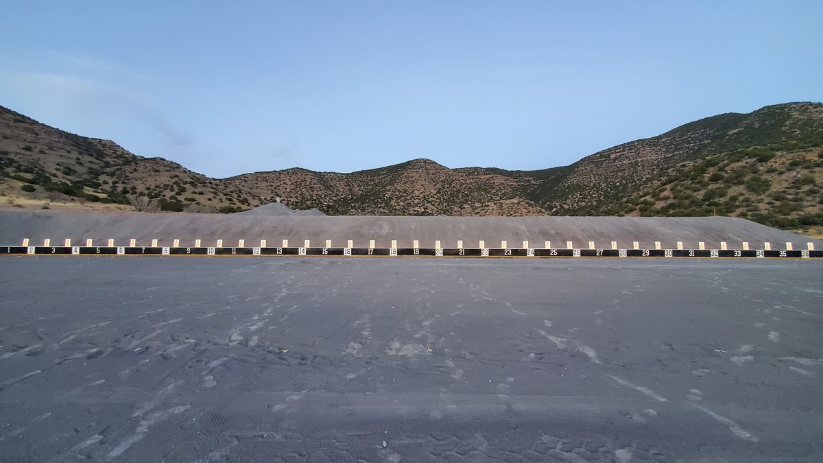 An outdoor qualification range in late light, its full line of hit-sensing targets standing along the berm.