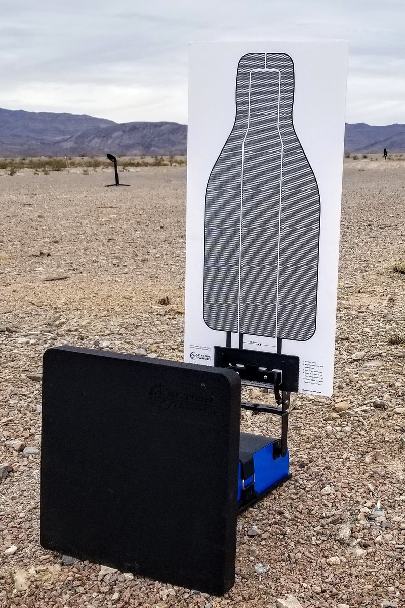 A HexLink conductive target raised on a blue lift unit behind a black rubber block ballistic stand on a desert range, with a second target standing downrange.