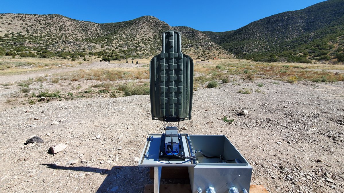 A green E-Type silhouette mounted on its lift unit at an outdoor range.