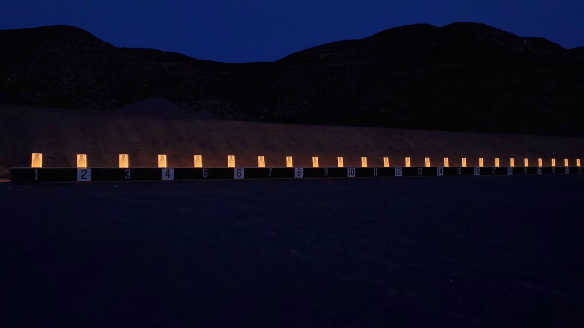 An AutoTargets range at night, its line of targets lit along the berm.
